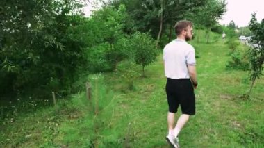 Doğada yapayalnız bir yürüyüş, yeşilliklerle çevrili genç adam, açık hava ve rahatlama temalı içerik için mükemmel.