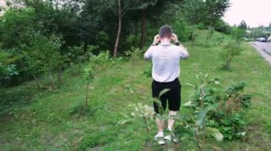 Etrafı yeşilliklerle çevrili, sakin bir park ortamında yürüyen bir adam. Yaşam tarzı ve doğa odaklı videolar için harika.