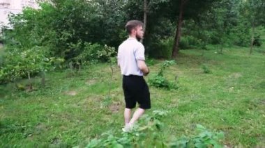 Etrafı yeşilliklerle çevrili, sakin bir park ortamında yürüyen bir adam. Yaşam tarzı ve doğa odaklı videolar için harika.