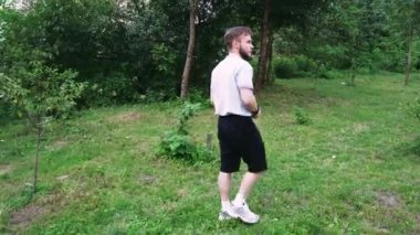 Etrafı yeşilliklerle çevrili, sakin bir park ortamında yürüyen bir adam. Yaşam tarzı ve doğa odaklı videolar için harika.