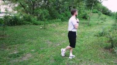 Çimenli bir yolda yürüyen bir adam doğal bir manzaranın huzurunun tadını çıkarır. Rahatlama ve açık hava içeriği için mükemmel.