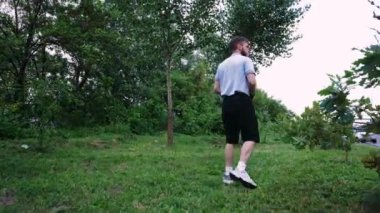 Çimenli bir yolda yürüyen bir adam doğal bir manzaranın huzurunun tadını çıkarır. Rahatlama ve açık hava içeriği için mükemmel.