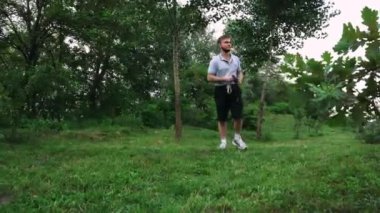 Yeşil yemyeşil bir parkta tek başına yürüyen bir adam, doğa tarafından çevrelenmiş sessiz bir anın tadını çıkarıyor. Rahatlama temaları için harika
