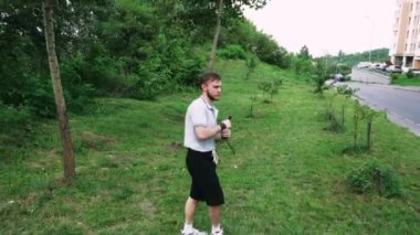 Yeşil yemyeşil bir parkta tek başına yürüyen bir adam, doğa tarafından çevrelenmiş sessiz bir anın tadını çıkarıyor. Rahatlama temaları için harika