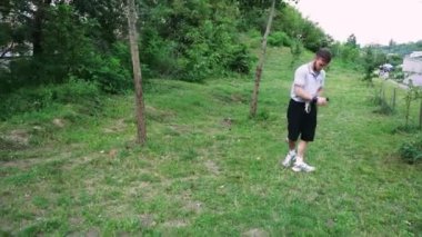 Yeşil yemyeşil bir parkta tek başına yürüyen bir adam, doğa tarafından çevrelenmiş sessiz bir anın tadını çıkarıyor. Rahatlama temaları için harika