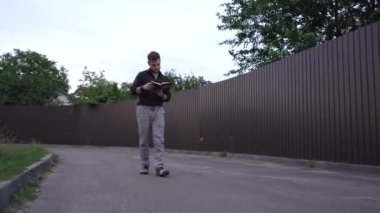 Bir adam, elinde bir kitapla, kahverengi metal bir çitin arkasında huzurlu bir şekilde yürümekten hoşlanır. Bu huzurlu sahne görsel rahatlama, huzur ve doğa keşfi içindir.