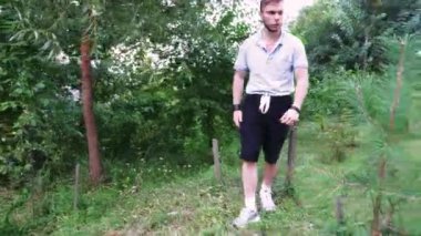 Çimenli, yeşil bir arazide sıradan bir gezinti, genç bir adam doğada huzurlu bir yürüyüşün tadını çıkarıyor.