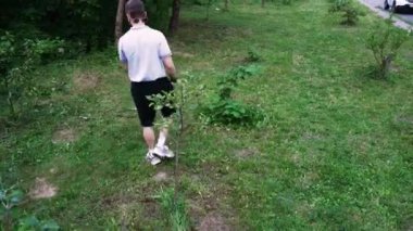 Çimenli bir yolda yürüyen, doğal bir ortama dalmış bir adamın arka görüntüsü. Açık hava ve yaşam tarzı içeriği için ideal