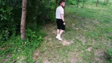 Çimenli bir yolda yürüyen, doğal bir ortama dalmış bir adamın arka görüntüsü. Açık hava ve yaşam tarzı içeriği için ideal