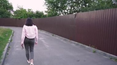 Yaşam tarzı ya da eğlence videoları için ideal. Sessiz bir yolda yürüyen genç bir kadın kitap okuyor ve doğada huzurlu bir anın tadını çıkarıyor.