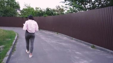 Yaşam tarzı ya da eğlence videoları için ideal. Sessiz bir yolda yürüyen genç bir kadın kitap okuyor ve doğada huzurlu bir anın tadını çıkarıyor.
