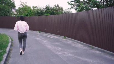 Yaşam tarzı ya da eğlence videoları için ideal. Sessiz bir yolda yürüyen genç bir kadın kitap okuyor ve doğada huzurlu bir anın tadını çıkarıyor.