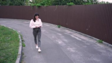 Asfalt yolda yürüyen bir kadının şehir ortamını rahatlıkla birleştirdiği sıradan bir sahne. Yaşam tarzı ve modern şehir içeriği için ideal