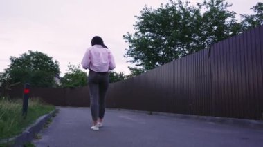 Genç bir kadın kitap okurken sessiz bir yolda yürüyor, dışarıda huzurlu bir anın tadını çıkarıyor. Yaşam tarzı ya da eğlence temalı videolar için mükemmel
