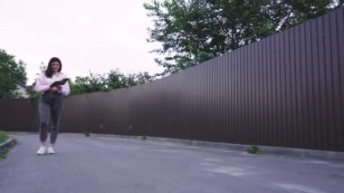 Genç bir kadın kitap okurken sessiz bir yolda yürüyor, dışarıda huzurlu bir anın tadını çıkarıyor. Yaşam tarzı ya da eğlence temalı videolar için mükemmel