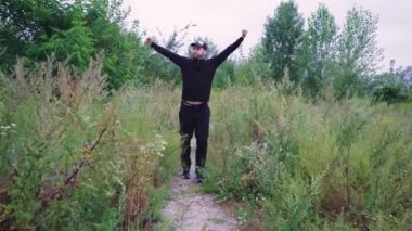 Vahşi bitki örtüsüyle çevrili doğa yolunda seyahat eden bir insan. Adam siyah eşofman ve şapka giyiyor. Doğa yürüyüşleri, yürüyüş ya da sessiz doğa için idealdir.