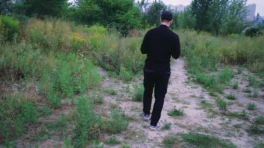 Yalnız bir adam yeşilliklerle çevrili kırsalda yeşil bir yol boyunca yürüyor. Yürüyüş, eğlence ya da macera için ideal
