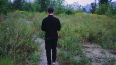 Yalnız bir adam yeşilliklerle çevrili kırsalda yeşil bir yol boyunca yürüyor. Yürüyüş, eğlence ya da macera için ideal