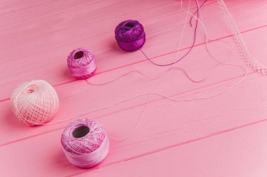 Ahşap pembe bir yüzey üzerinde pembe ve mor bir iplik rulosu, dekorasyon, hediye paketi ve dikiş için mükemmel.