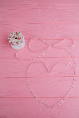 Beautiful lace ribbon, elegantly wrapped in the shape of a heart on a pink background, adds charm to homemade projects and crafts clipart