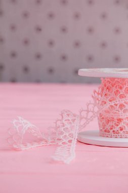 Vertical photo of pink lace ribbon on a decorative spool is perfect for arts and crafts and adds a vintage touch to any project clipart