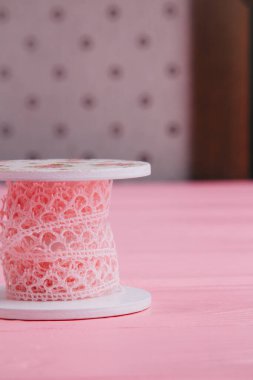 Vertical photo of pink lace ribbon on a decorative spool is perfect for arts and crafts and adds a vintage touch to any project clipart