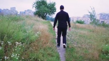 Çevresi yemyeşil bitki örtüsüyle çevrili doğa yolunda yürüyen bir adam. Açık hava, doğa keşfi veya seyahatle ilgili videolar için mükemmel.