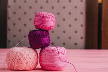 Pembe gözlüklü ve dantel kurdeleli iplik topları. Tekstil, örgü ve el işi temaları için ideal.