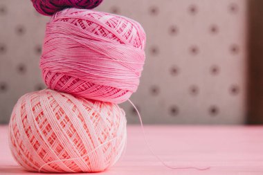 Pembe gözlüklü ve dantel kurdeleli iplik topları. Tekstil, örgü ve el işi temaları için ideal.