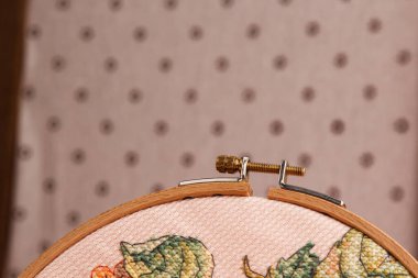 Parlak çiçek desenli nakışlı bir halka soluk pembe arka planda yakın plan çekilir. Kendin Yap Estetik Kurulumu