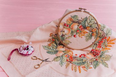 Close-up image of embroidery hoops with floral design and scissors in gold color, perfect for illustration of handmade textile art and creativity clipart