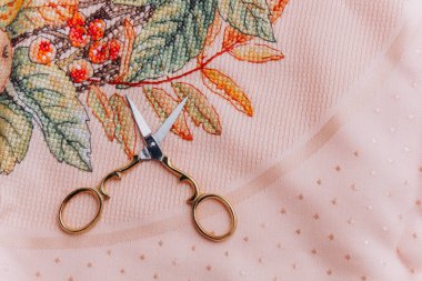 Close-up image of embroidery hoops with floral design and scissors in gold color, perfect for illustration of handmade textile art and creativity clipart