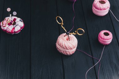 Siyah tahtalardaki altın çelik makas pembe ipek bir ipliğe yapışmış.