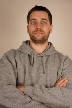 Çapraz eller. Ön manzara. Yakışıklı adammış. Tarafsız bir arkaplan. Sıradan giyinmiş bir adam. Genç bir erkek kameranın önünde duruyor. Adam kameraya bakıyor.