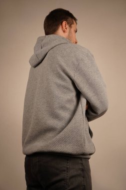 Adam yana bakıyor. Çapraz eller. Yan görüş. Yakışıklı bir erkek. Genç adam kameranın önünde duruyor. Tarafsız bir arkaplan. Sıradan giyinmiş bir adam.