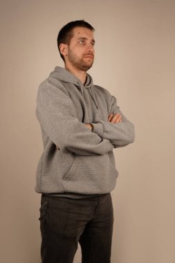 Kameraya bakan kişi ellerini çapraz yapmış. Yakışıklı bir adam. Tarafsız bir geçmişle kameranın önünde duran genç adam. Yan görünüşlü sıradan giysili bir adam.