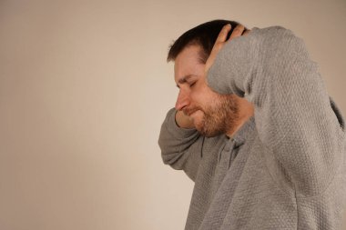 Umutsuz, sinirli sakallı adamın fotoğrafı ellerini kafasından ayırmıyor ve gözlerini kapatıyor. Depresyondaki adam. Genç adamın portresi elleriyle kulaklarını kapatıyor ve gözlerini gri renkte kapalı tutuyor.