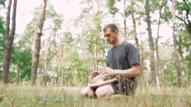 Handpan oyuncusu doğada huzurlu anların tadını çıkarıyor, müzikal ifade ile açık hava meditasyonunu birleştiriyor.