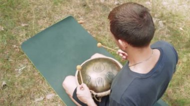 Huzurlu bir ormanda davul çalan adam müzik ve farkındalık yoluyla doğayla bağlantı kuruyor.