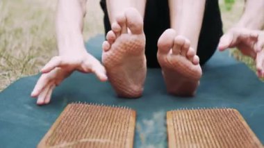 Genç bir adamın bacaklarında çivi izleri var. Bir adam yeşil bir paspasın üzerine oturur ve çivi izleri ve doğa ile birleşmiş sağlıklı bir atmosfer gösterir.