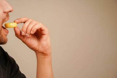 Young bearded man eating a ring-shaped snack holding it in his hand, closeup shot. Unhealthy but tempting fast food clipart