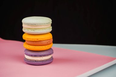 Yumuşak pembe bir zemin üzerine dizilmiş renkli badem kurabiyesi koleksiyonu. Fotoğraf bu klasik Fransız pastasının narin ve sanatsal doğasını vurguluyor.