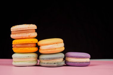 Çok renkli badem kurabiyeleri bir piramide istiflenmiş. Sarı, yeşil ve pembe badem kurabiyeleri zarif bir şekilde bir kaydırağın içine istiflenir. Tatlının tadı ve kalitesi gözler önüne serilir.