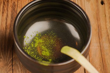 Siyah bir kibrit kutusu ahşap bir masanın üzerinde duruyor. Yeşil toz kibrit kasesine dökülür.