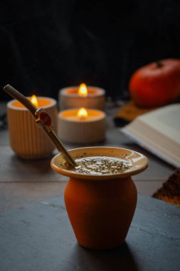 Matcha çayı yapmak için geleneksel bambu çırpıcı tutan bir adamın yakın çekimi. Çay kültürü, farkındalık ve Asya teması için mükemmel. Masanın üzerinde bir bardak kibrit çayı duruyor.