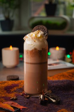 Chocolate milkshake in a glass cup. On the autumn background. Serve with whipped cream in a glass on the table. Free space for text clipart