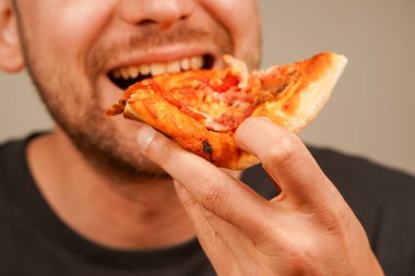 Bir adam bir dilim peynirli pizzayı seviyor, klasik atıştırmanın tadını çıkarıyor. Yemek ve restoran görselleri için mükemmel bir konsept.