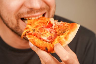 Bir adam bir dilim peynirli pizzayı seviyor, klasik atıştırmanın tadını çıkarıyor. Yemek ve restoran görselleri için mükemmel bir konsept.
