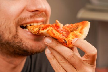 Bir adam bir dilim peynirli pizzayı seviyor, klasik atıştırmanın tadını çıkarıyor. Yemek ve restoran görselleri için mükemmel bir konsept.
