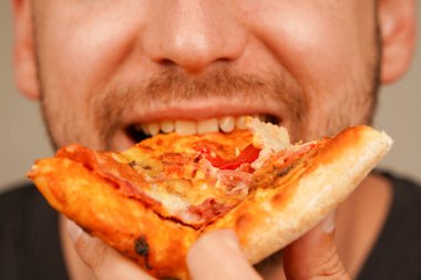 Bir adam bir dilim peynirli pizzayı seviyor, klasik atıştırmanın tadını çıkarıyor. Yemek ve restoran görselleri için mükemmel bir konsept.